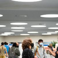 Long shot of guests wearing masks and mingling.